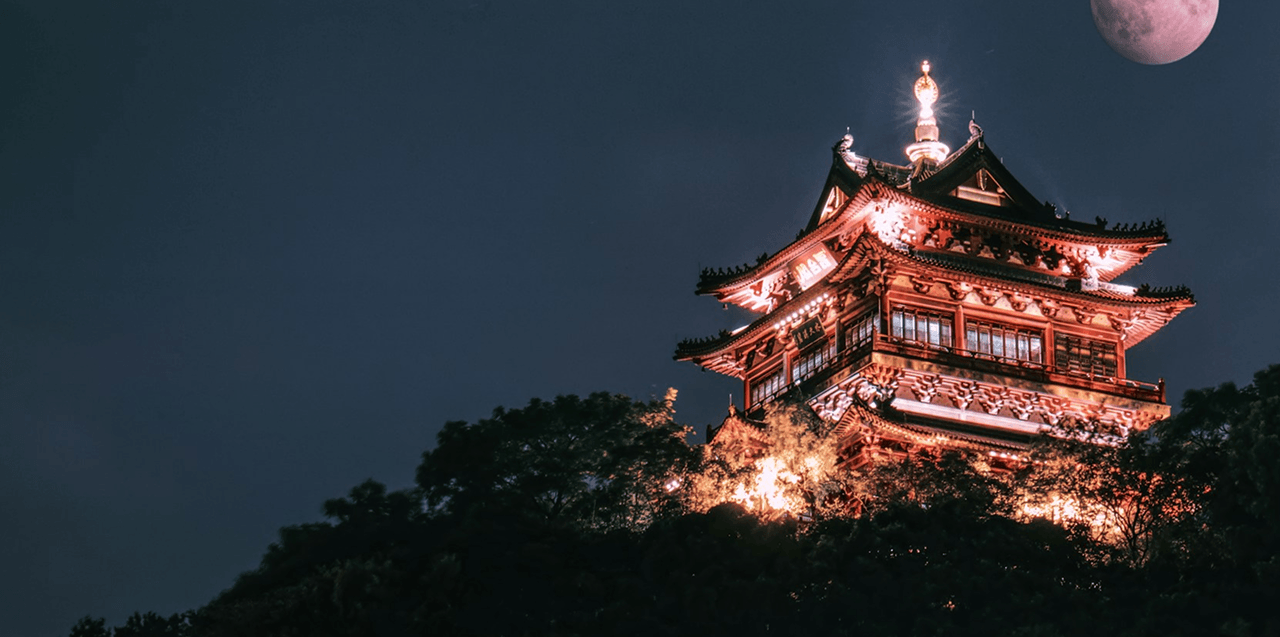 Templo iluminado no topo de uma colina à noite, na China