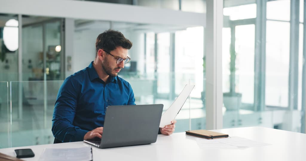 Homem em escritório utilizando computador portátil para participar de MBA em Gestão Tributária.