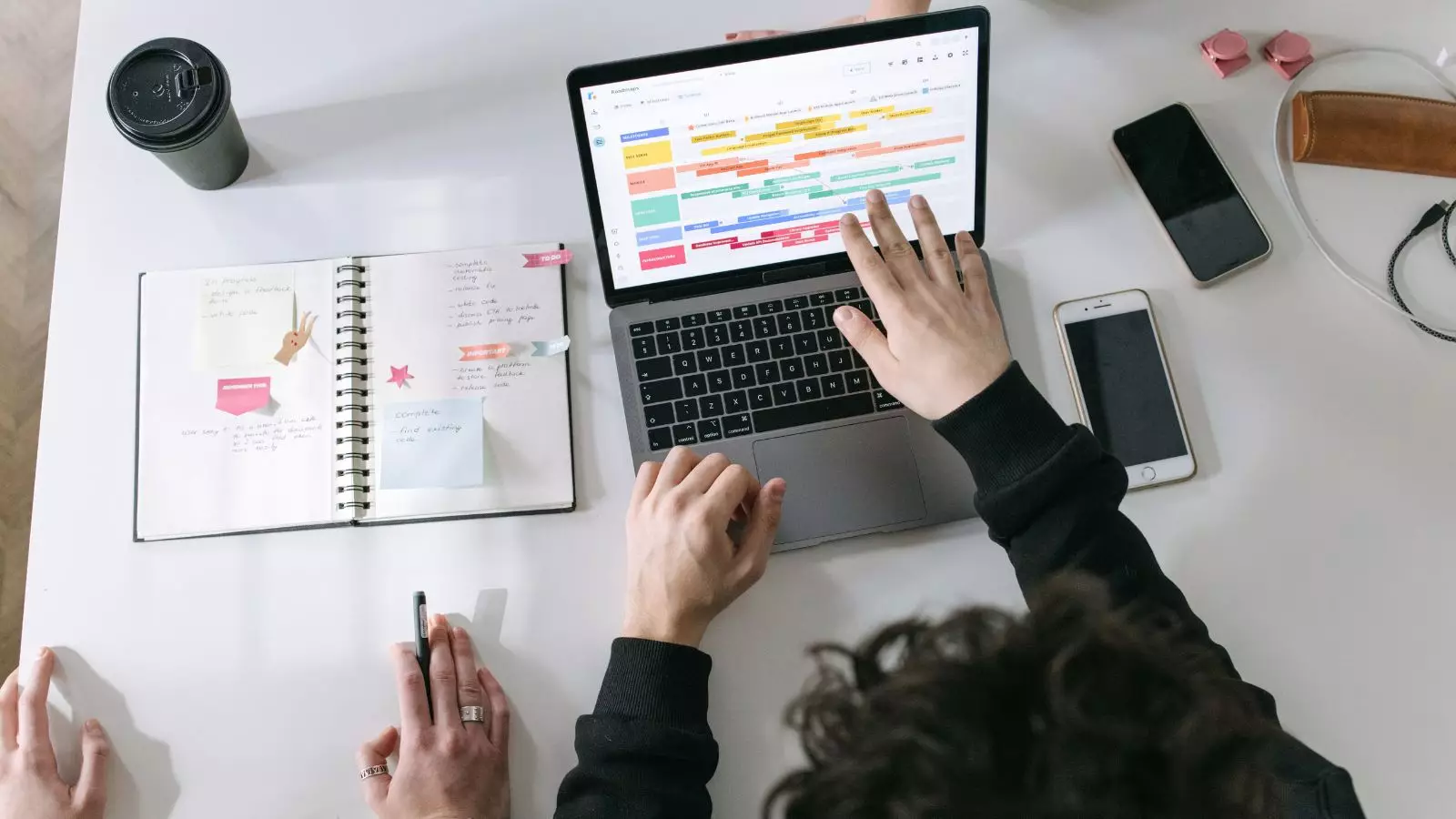 Pessoa organizando tarefas em um notebook e planner para melhorar a produtividade.