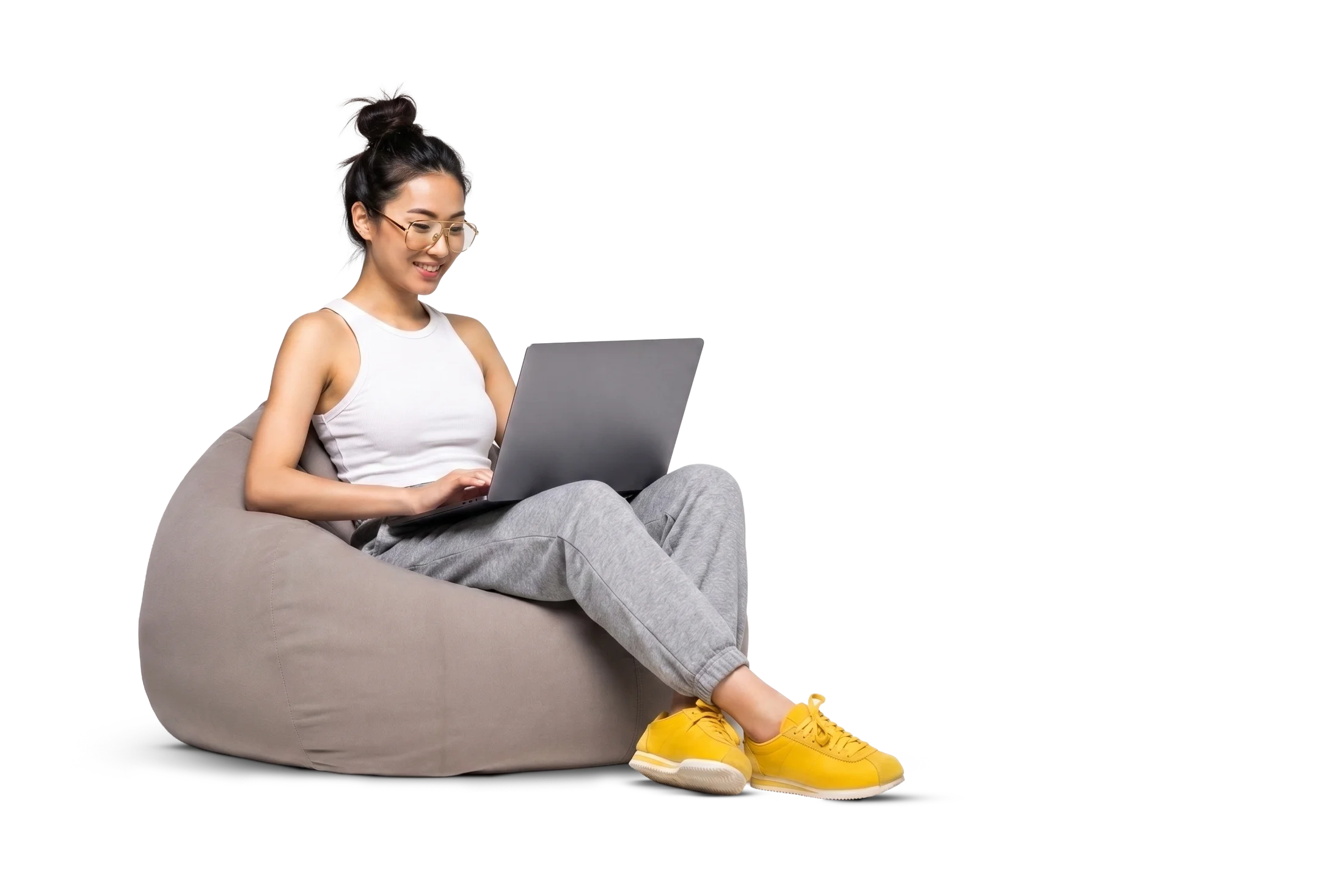 Pessoa sentada em um pufe, digitando em um notebook no colo